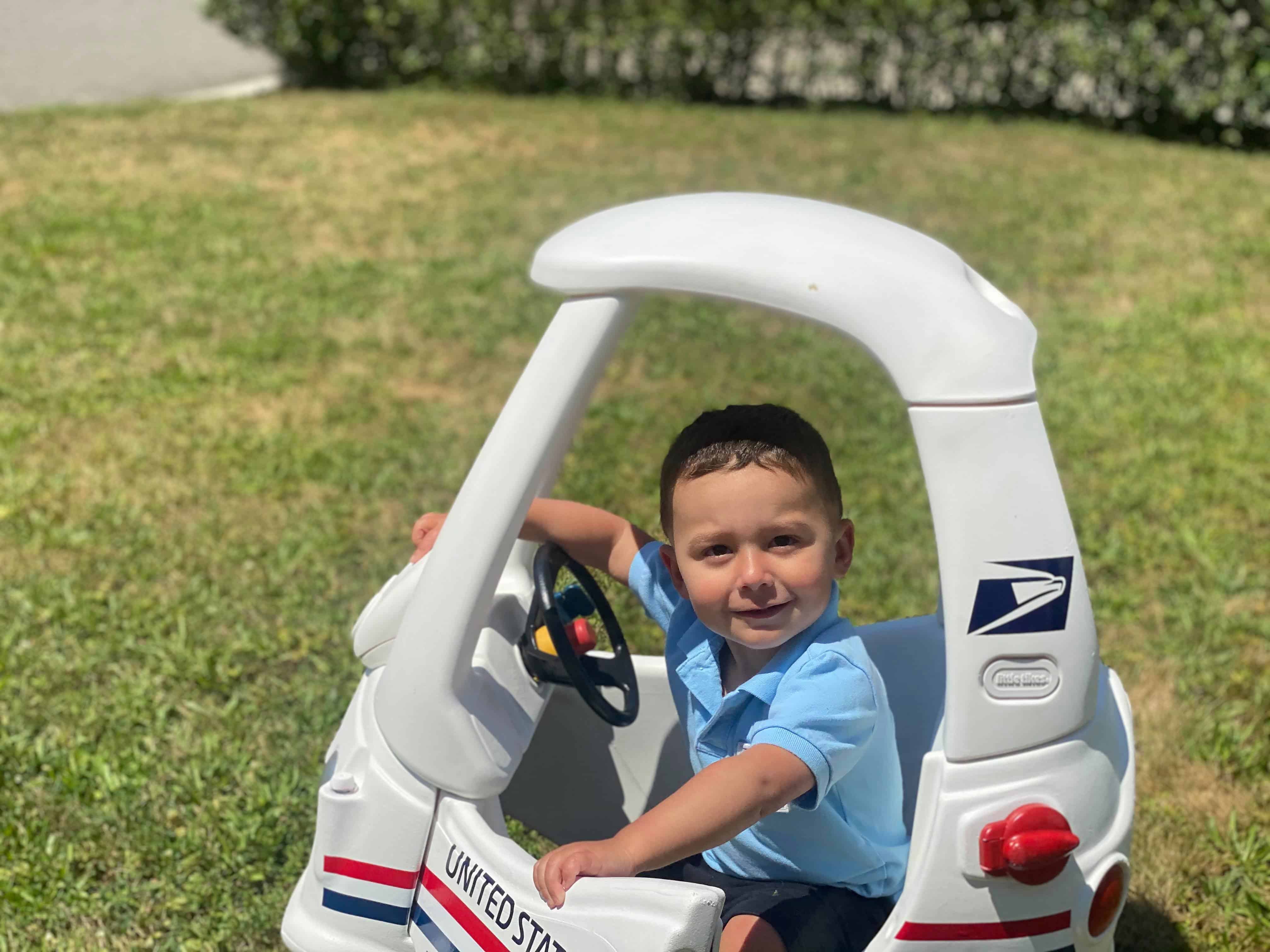 Little boy in USPS Mail Truck Cozy Coupe Makeover