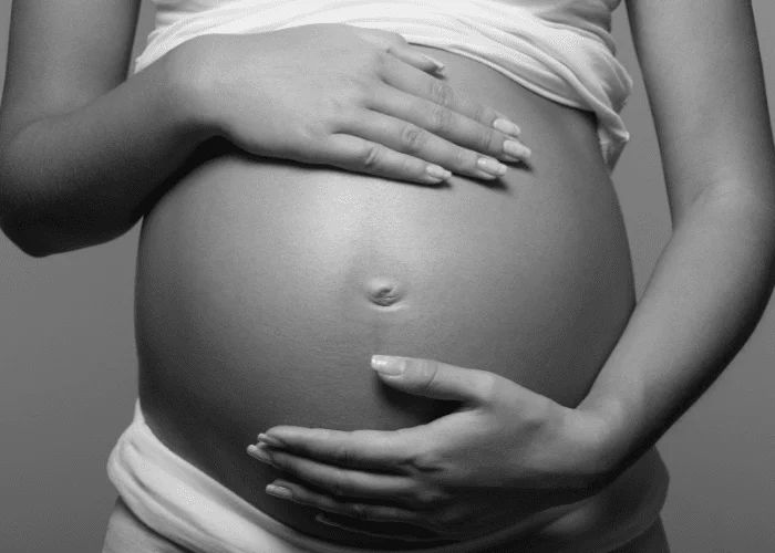 image shows hands cradling a pregnant tummy