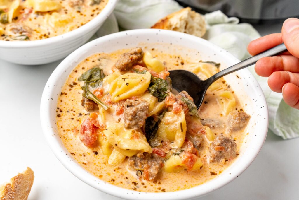 image shows a bowl of slow cooker tortellini soup