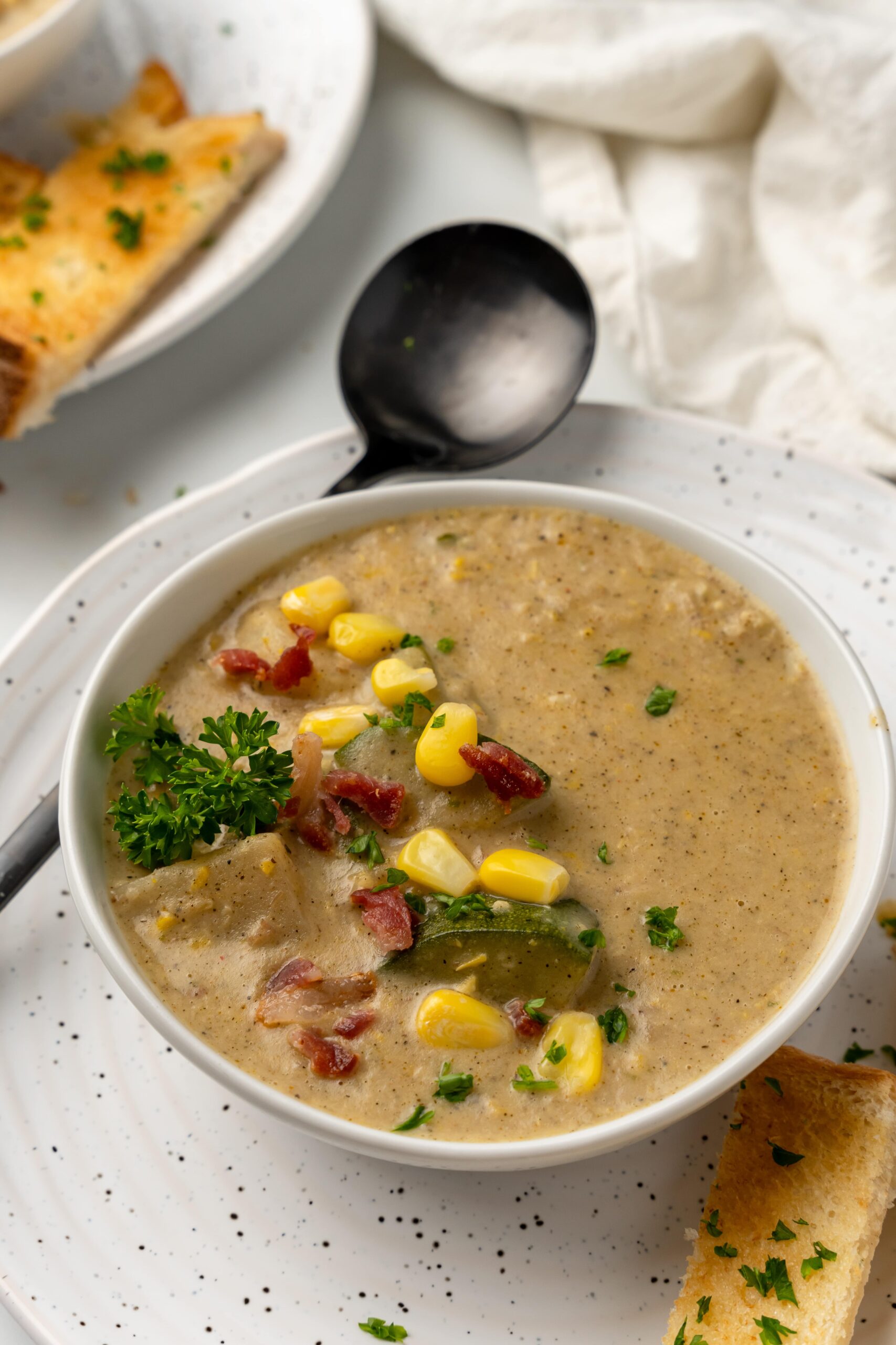 bowlful of corn and zucchini soup made with bacon and potatoes
