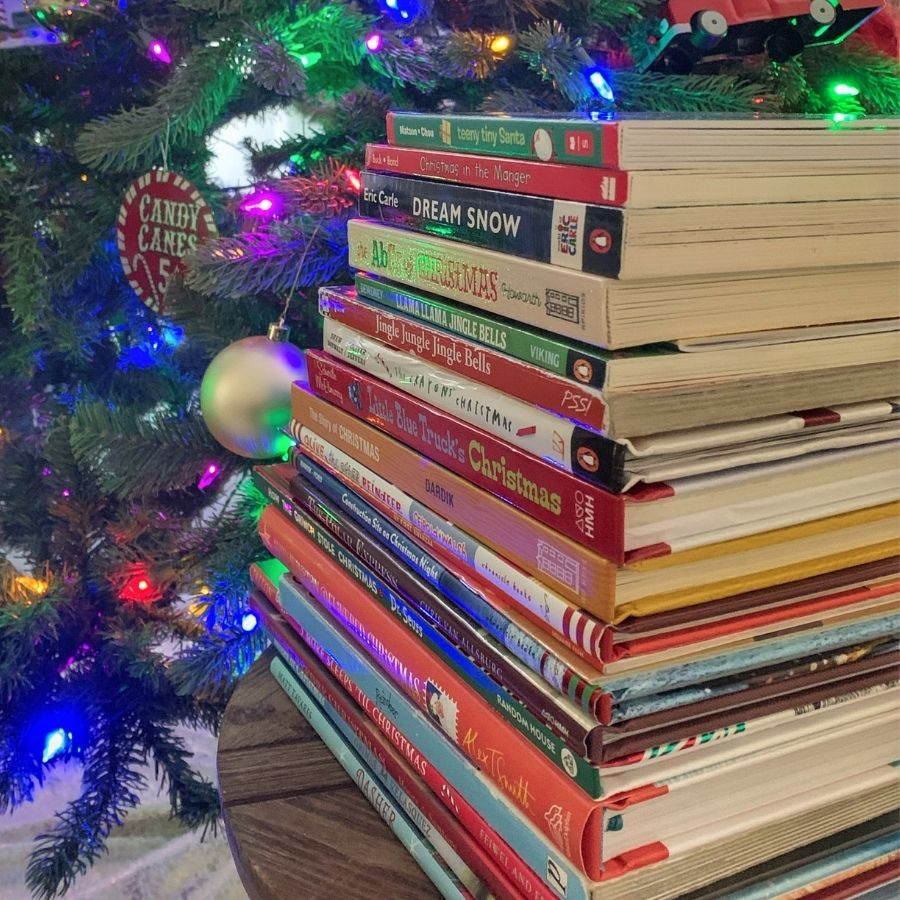 image shows a stack of Christmas books in front of the Christmas tree
