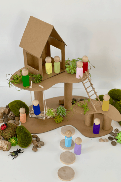 shows a treehouse made of cardboard with wooden figures