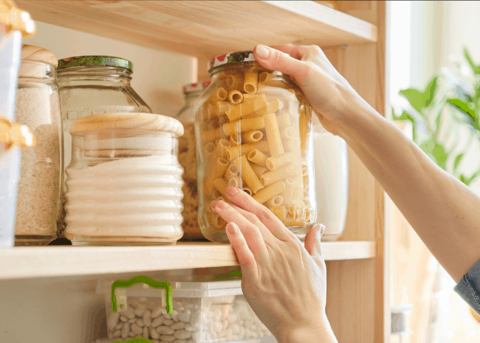 shows a hand grabbing a jar of dry pasta