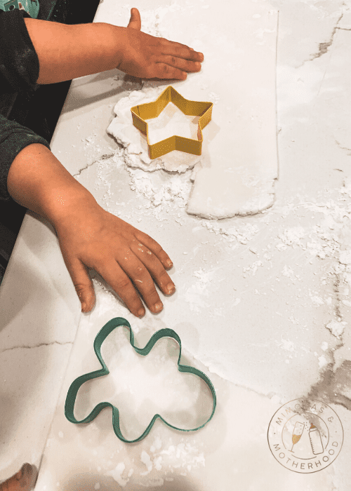 image shows hands cutting out air dry clay ornaments using cookie cutters