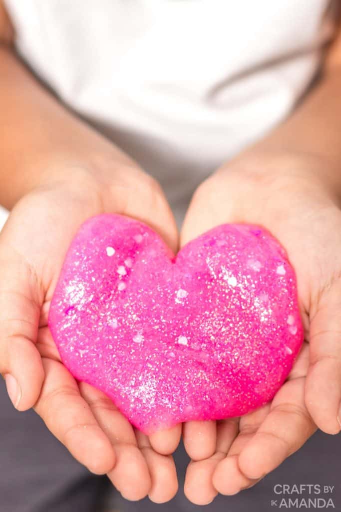 image shows hands holding a heart shaped lump of pink slime