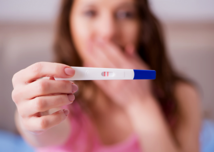 image shows a woman holding a pregnancy test