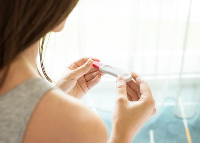 image shows a person holding a pregnancy test