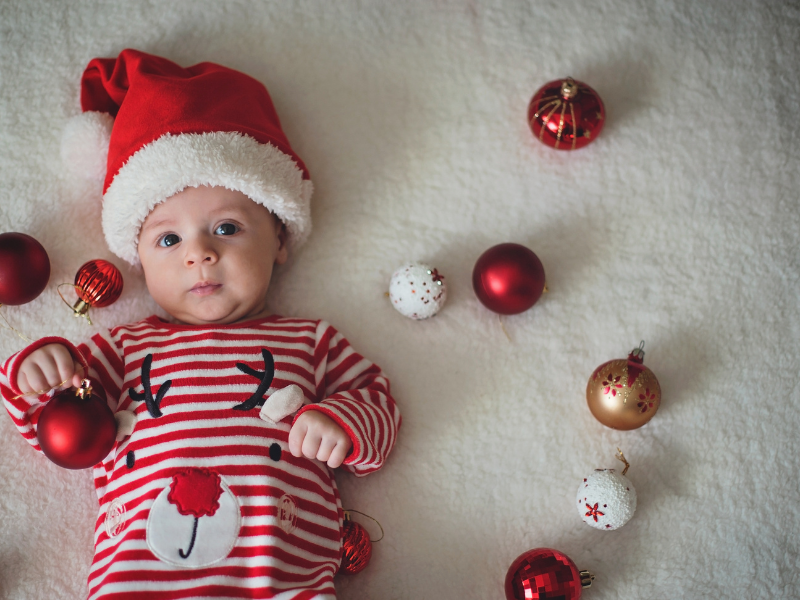 baby laying with Christmas ornaments