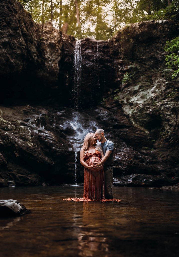 couple standing in water during maternity photoshoot