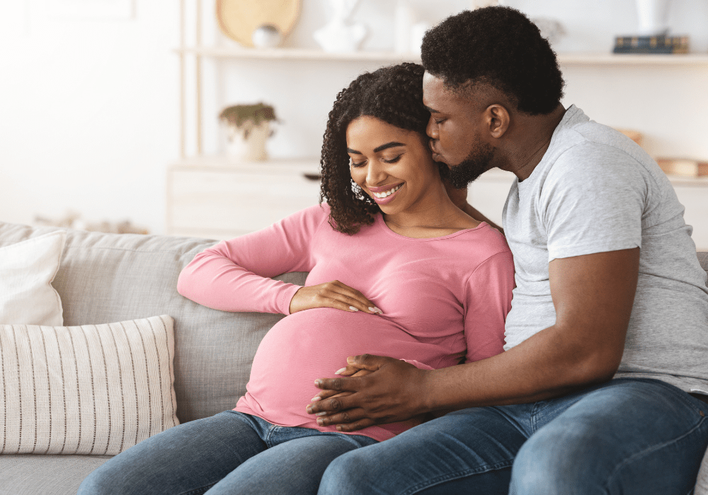 pregnant couple kissing on couch