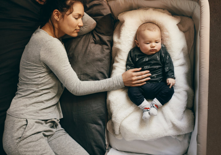 image shows a mom and baby asleep in a bedside sleeper