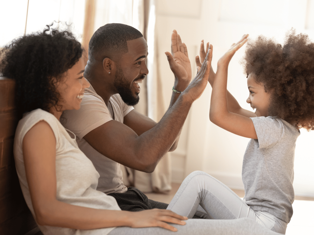 image shows two parents high fiving a child