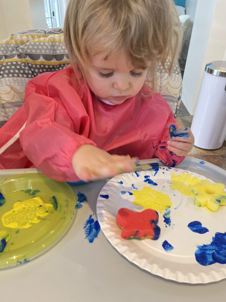 image shows a child playing with paint