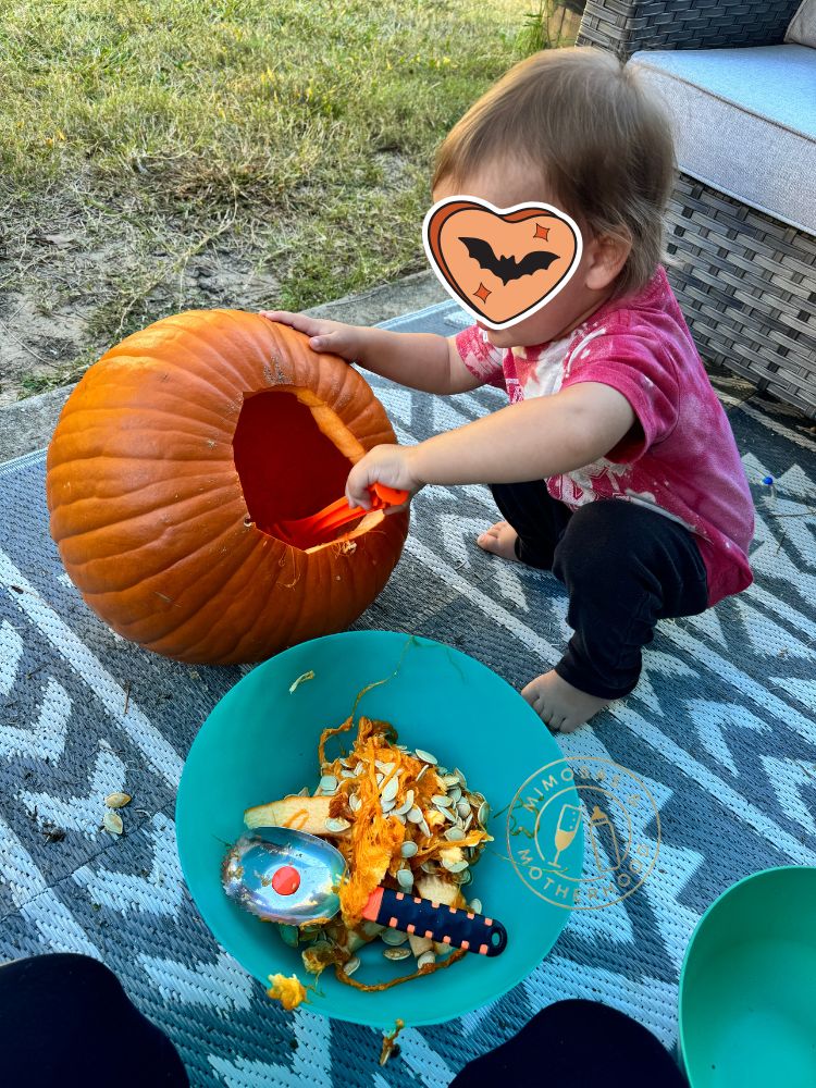 Image shows a toddler carving a pumpkin
