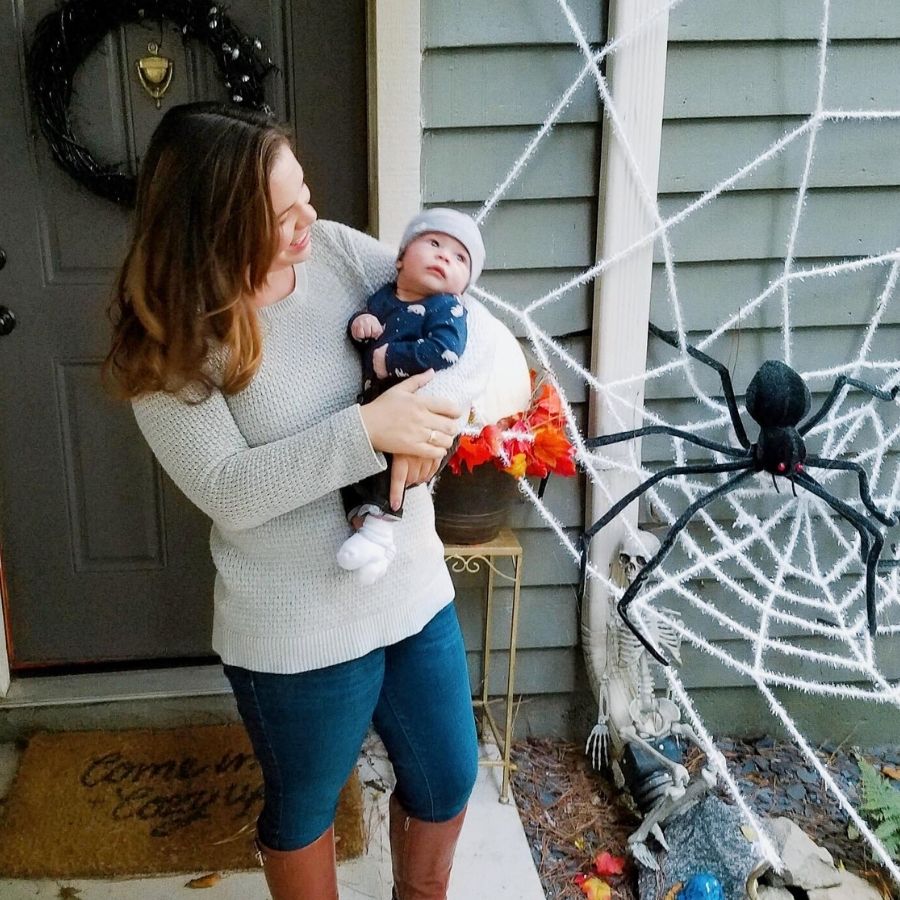 woman holding a baby in front of a halloween spiderweb