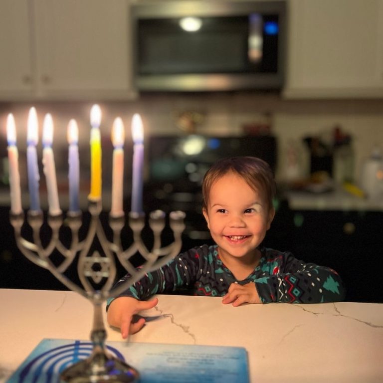 child with lit menorah during Hanukkah
