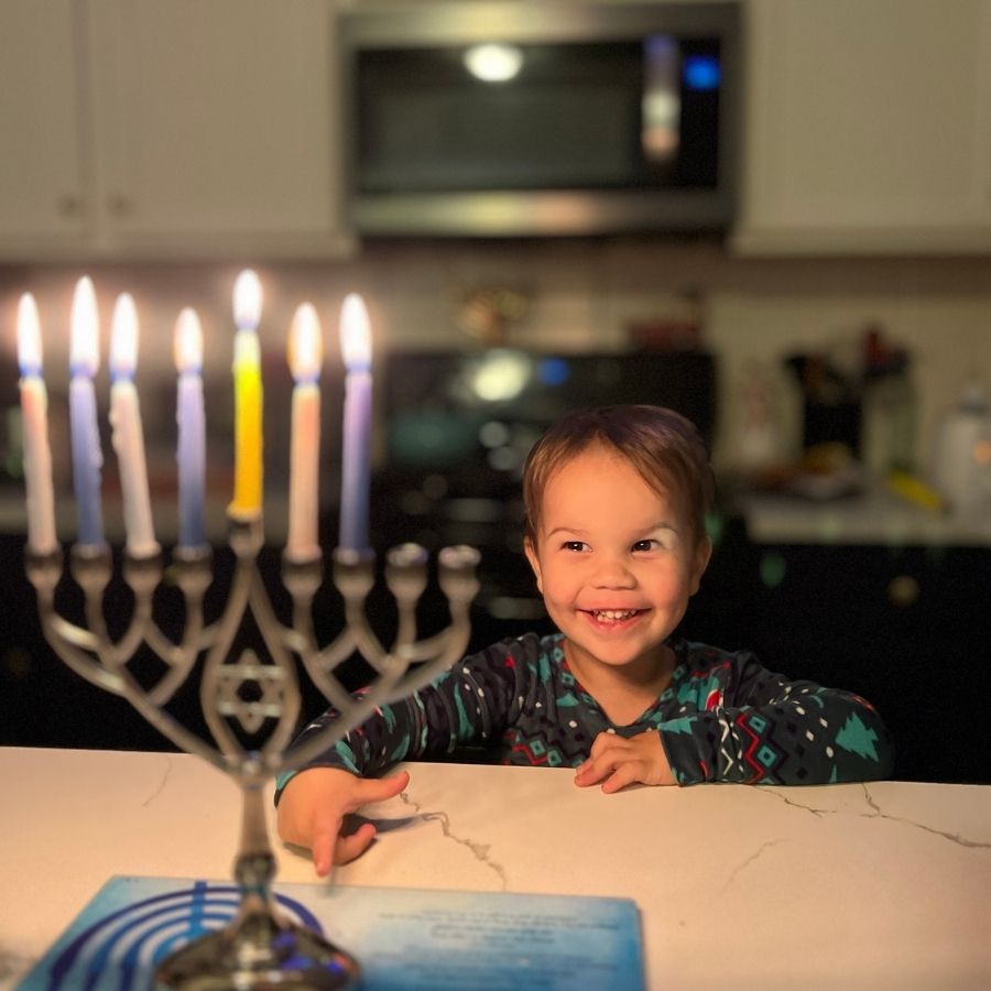 child with lit menorah during Hanukkah