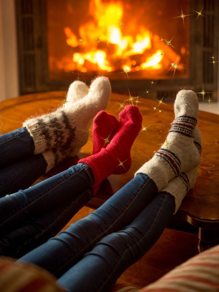 three pairs of feet in socks in front of a fire