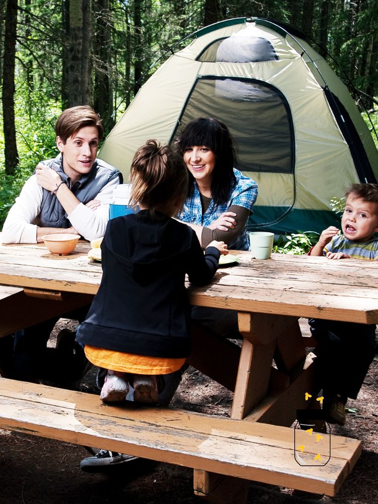 a family at a picnic table in front of a tent